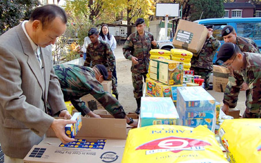 Park Heung-sik, director of Namsan Orphanage in Seoul, looks through some of the donated food as soldiers from the 94th Military Police Battalion arrange the goods.