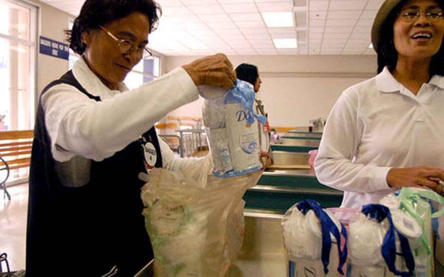 Rosa Rafael helps a customer Thursday at Yokosuka Naval Base’s commissary in Japan, where double-bagging is done only by request.