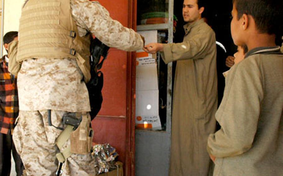 A U.S. Marine interacts with shopkeepers in Husaybah, Iraq, on Tuesday. Providing for the day-to-day needs of local Iraqis here is now a priority for following last week’s battles.