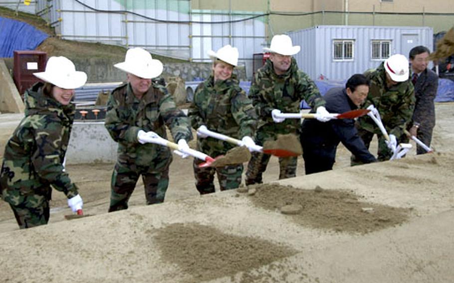 Members of the Osan Air Base community throw the first shovels of dirt during a groundbreaking ceremony for a new housing tower Tuesday morning.