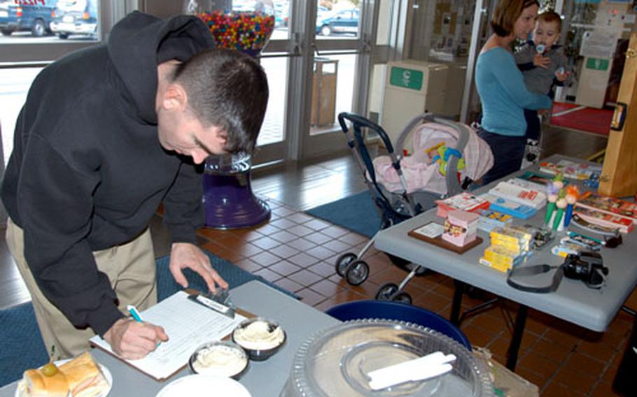 While his wife and kids wait in the background, Airman 1st Class Steve O’Brien, a firefighter at Misawa Air Base, Japan, signs a pledge Thursday to be tobacco-free for 24 hours during the base’s “Great American Smokeout.” Medical and health officials are trying to encourage smokers to quit “cold turkey” in exchange for free turkey sandwiches.