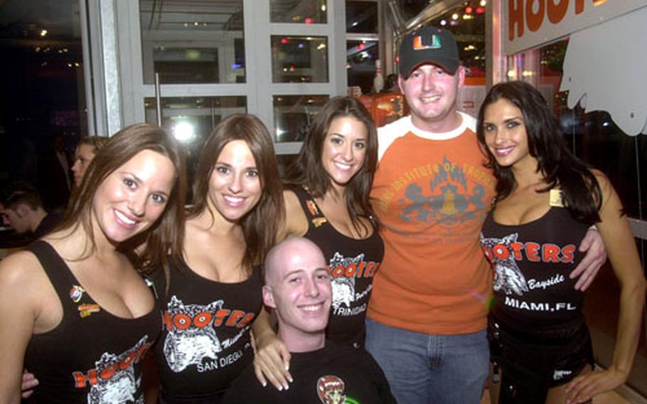 Senior Airman Doug Collins, right, and Air Force Staff Sgt. Edward Mann pose with American Hooters girls Friday at the grand opening party for the Neunkirchen Hooters, the first Hooters to open in Germany.