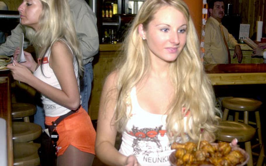 A German Hooters girl delivers a plate of chicken wings Friday night at the grand opening of the Hooters in Neunkirchen, Germany.