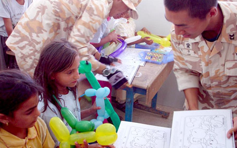 South Korean soldiers show Iraqi schoolchildren coloring books that were among the school supplies they helped distribute to the school. In all, the Taegu American School collected two big boxes of supplies to send to the Iraqi students.
