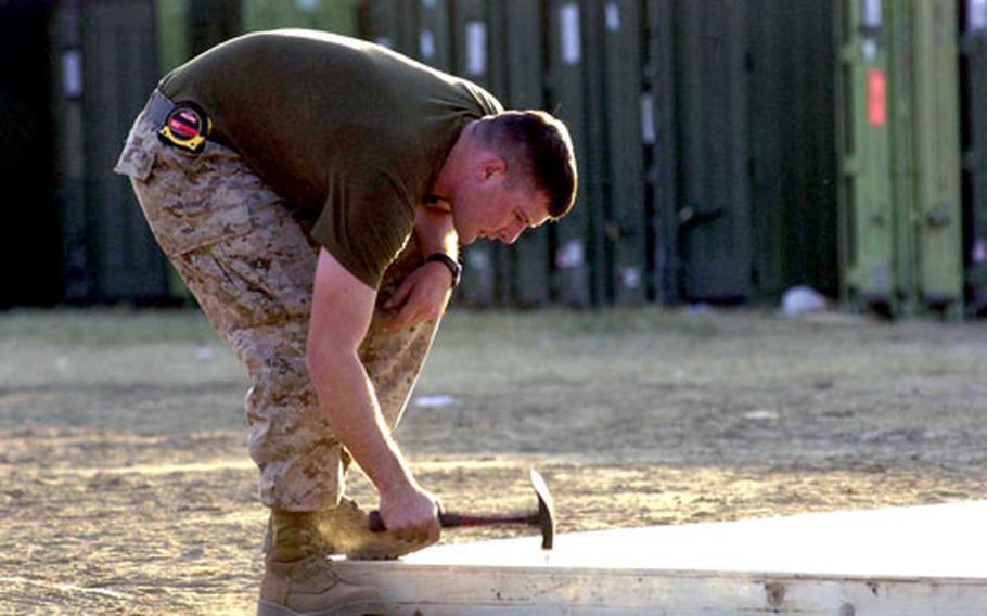 Cpl. Richard Book, a combat engineer with 9th Engineer Support Battalion, puts together a piece of decking in Shinkiari, Pakistan, just hours after arriving at the camp.