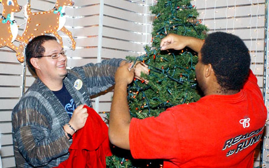 Marine Corps Exchange employees Luis Pena, at left, and Henry B. Rodgers decorate the inside the Marine Corps Air Station Iwakuni store.