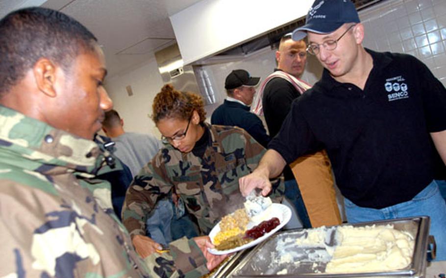 Master Sgt. Joey Blankenship serves Senior Airman James Watson a scoop of mashed potatoes during the annual Thanksgiving dorm feed in Building 539 Tuesday night at Misawa Air Base, Japan.