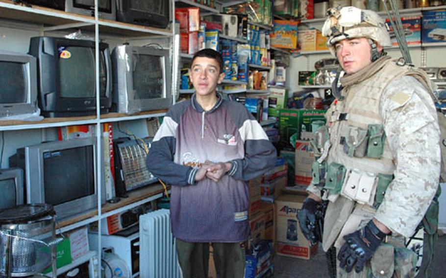 Lance Cpl. Michael Virts consults with an Iraqi store clerk about the television Virts' platoon pooled money to buy.