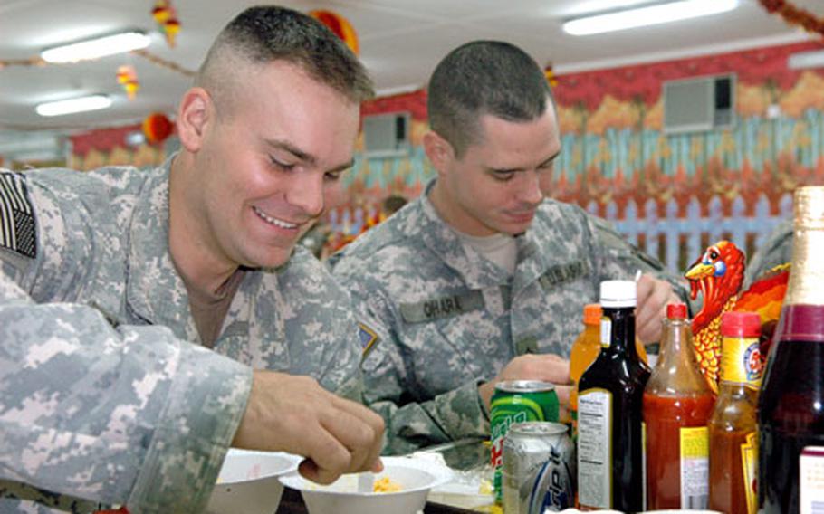 Spec. Timothy Sprague and Sgt. Morgan O'Hara of Company A, 3rd Battalion, 3rd Brigade, 101st Airborne Division, enjoy a Thanksgiving meal at the Camp Union dining facility in Baghdad's Green Zone.