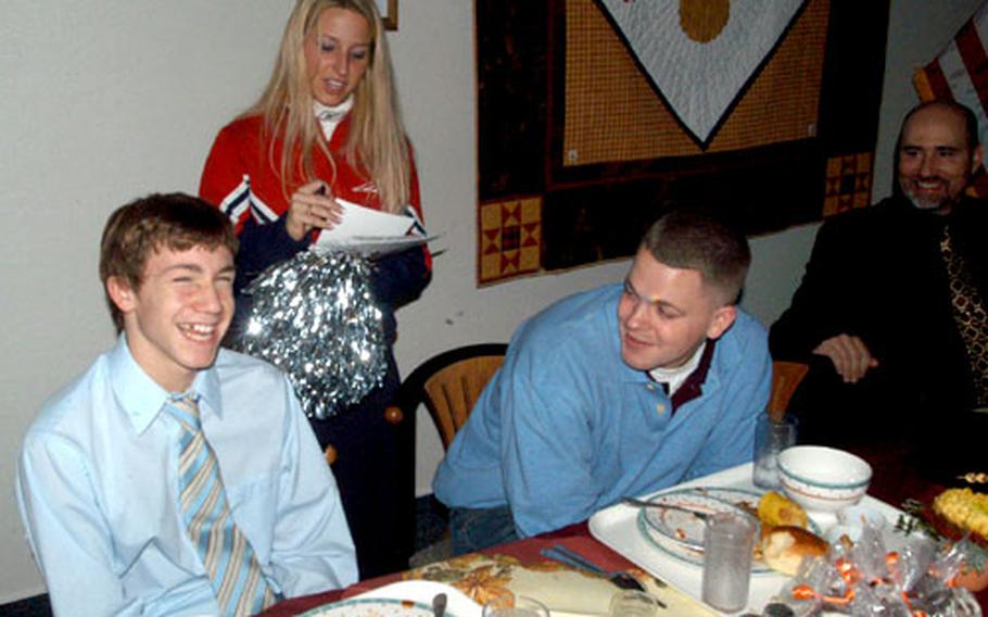 Neill Warrington, left, and his brother, Spc. Soren Hultman of the Hanau, Germany-based 127th Aviation Support Battalion, receive autographs from New England Patriots cheerleader Cara Orazietti on Thursday during a Thanksgiving lunch at Landstuhl Regional Medical Center. Four of the cheerleaders from the Super Bowl champions visited Landstuhl as part of a tour with musicians Trick Pony and John Popper.