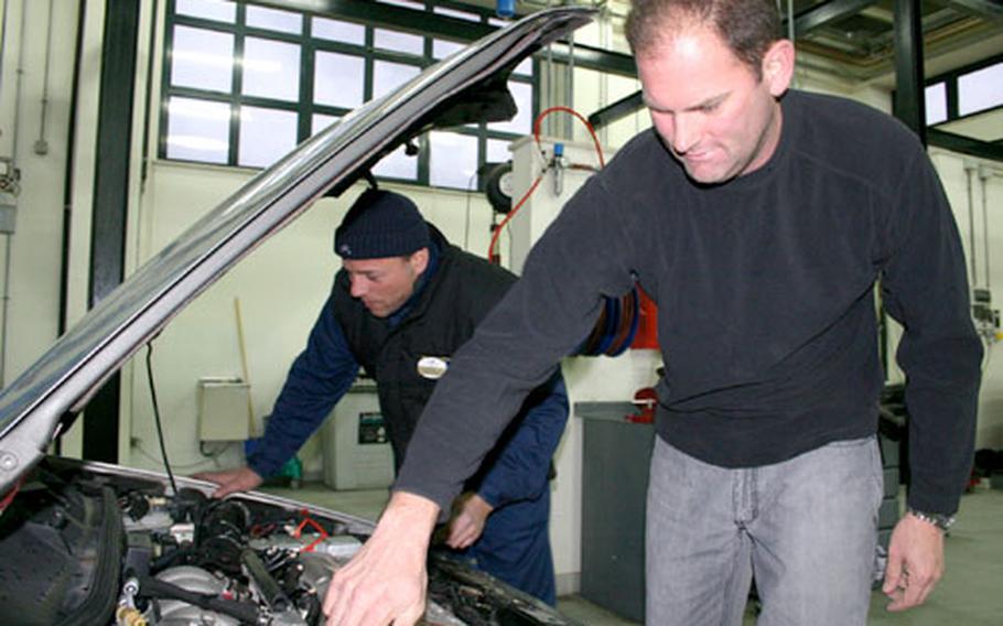 Chief Petty Officer John Whitley, foreground, checks the antifreeze level in his vehicle Tuesday while Massimo Quartucci, who works at the Auto Skills Center at Naval Support Activity Naples, Italy, checks over the engine’s hoses and belts. Whitley visited the center this week to winterize his car.