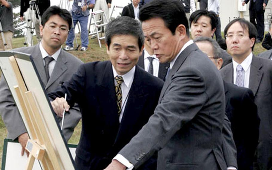 Naha Defense Facilities Administration Bureau Director General Masanori Nishi, left, briefs Foreign Minister Taro Aso, right, Friday about U.S. base relocation plans on Okinawa. Aso visited Schwab during a tour of Okinawa bases.