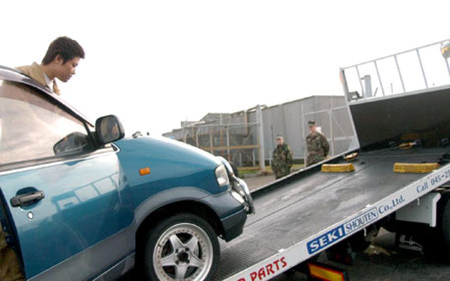 Seki Shouten employee Sho Aoi removes the last impounded car of the month from Yokosuka Naval Base, Japan, on Tuesday.