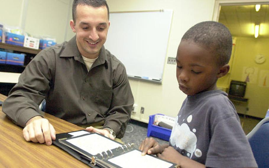 Navy Lt. Charles Charbonneau, an optometrist from U.S. Naval Hospital Okinawa, checks Zukeran Elementary School first-grader Antonio Mitchell's color vision during a vision and audiology screening at the school Wednesday.