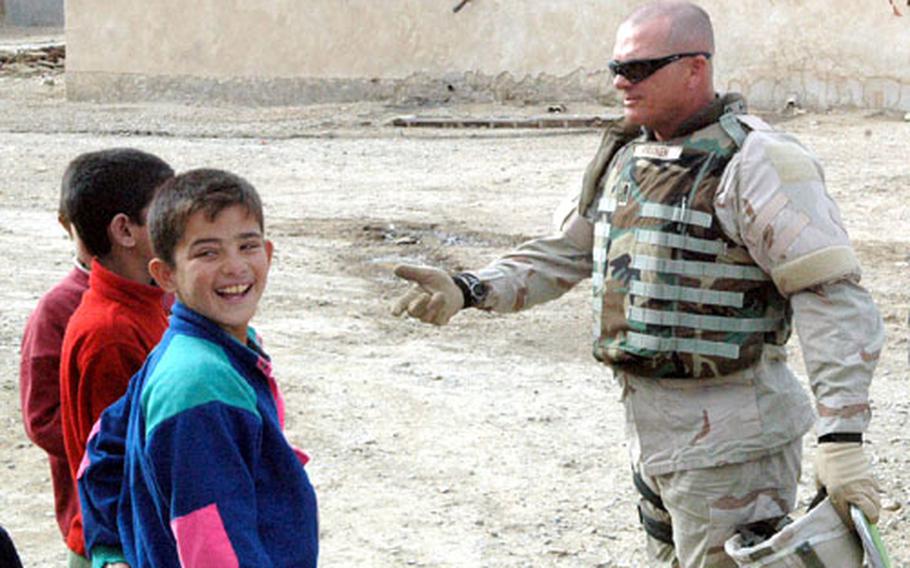 First Sgt. Troy Piirainen jokes with local children while questioning residents on the outskirts of Tal Afar about a string of roadside bombings. U.S. troops believe the bombs are being planted by cash-strapped local men paid by a local Sunni sheik who allegedly issued a directive, urging the killing of U.S. and Iraqi troops.