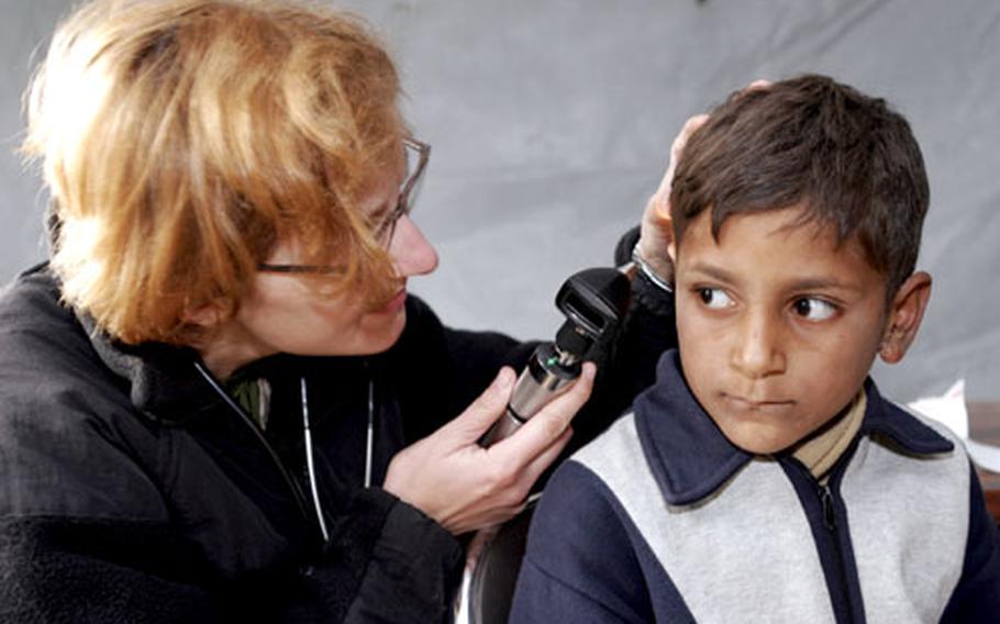 Navy Lt. Oksana Hirniak, a general medical officer from 3rd Marine Logistics Group, Okinawa, Japan, examines the 2,000th patient treated at the field hospital in Shinkiari, Pakistan, on Nov. 29. More than 200 Marines and sailors from Okinawa are deployed to Pakistan on an earthquake relief mission.