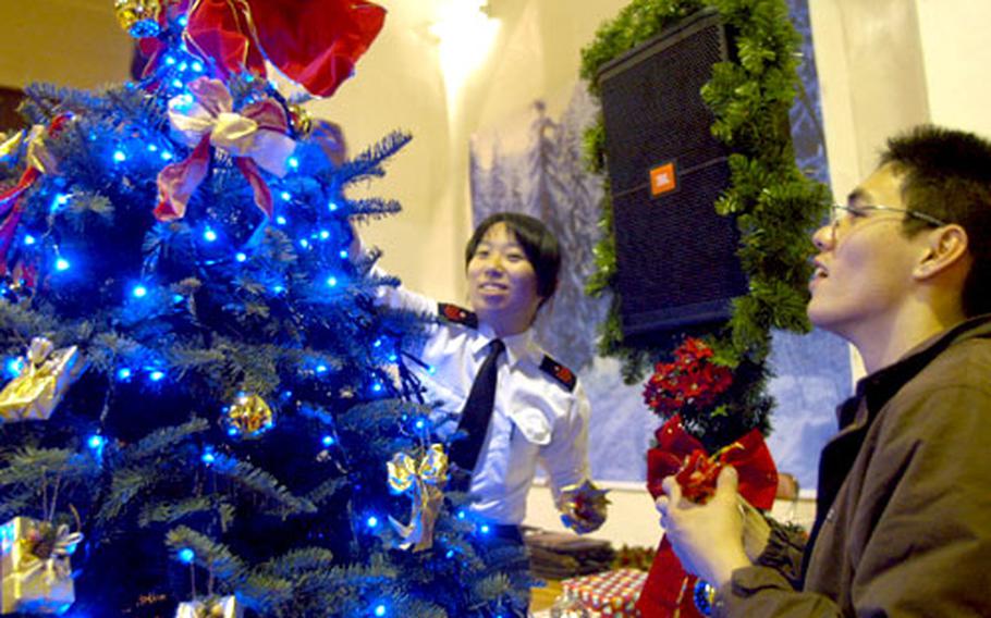 Shinya Shimada, right, and Toshie Ogane of the Japanese Maritime Self Defense Force 2nd Submarine Flotilla add the finishing touches to their tree Wednesday at Yokosuka Naval Base.