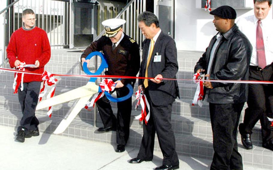 Cmdr. Bernard Wang, second from left, chief staff officer at Sasebo Naval Base, prepares to cut a ceremonial ribbon Thursday afternoon at the grand reopening of the Showboat Theater.