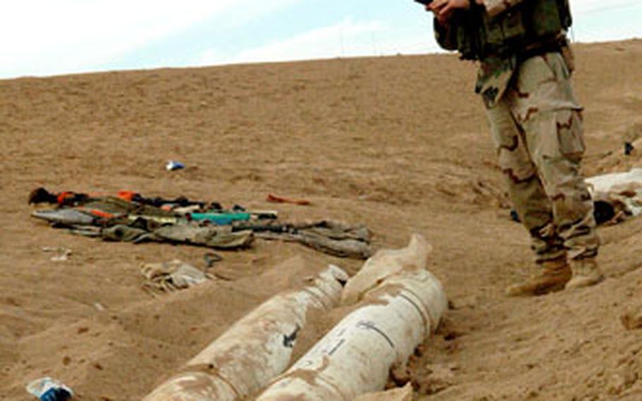 A bomb disposal expert prepares to destroy two French-made Roland surface to air missiles and an assortment of rocket-propelled grenades found on the outskirts of Bi’aj in northwestern Iraq on Friday. U.S. and Iraqi troops learned of the weapons cache during a cordon-and-search operation in the struggling town.