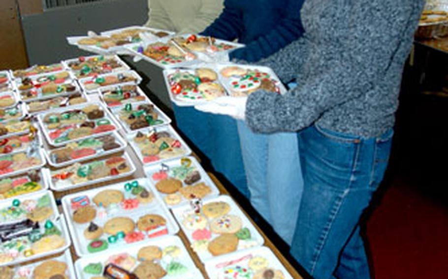 Anne Turnbull, far left, of the Family Support Center, and volunteers Marci Angelella, center, and Erin Cabot, stand next to dozens of cookie trays ready to be packaged during the annual holiday Cookie Caper on Monday morning at Misawa Air Base, Japan.