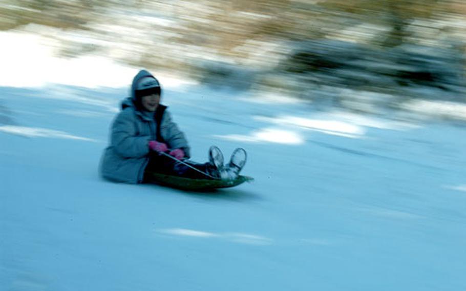 A child races along on a sled at snowy Namsan Park.