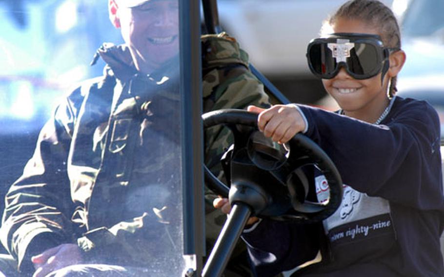 Phillip Savin, 11, drives a golf cart Wednesday at Misawa Air Base, Japan, with Tech. Sgt. Daniel Rice of the 35th Fighter Wing safety office while wearing vision-blurring goggles. The base’s helping agencies sponsored the event for National Drunk and Drugged Driving Prevention Month.