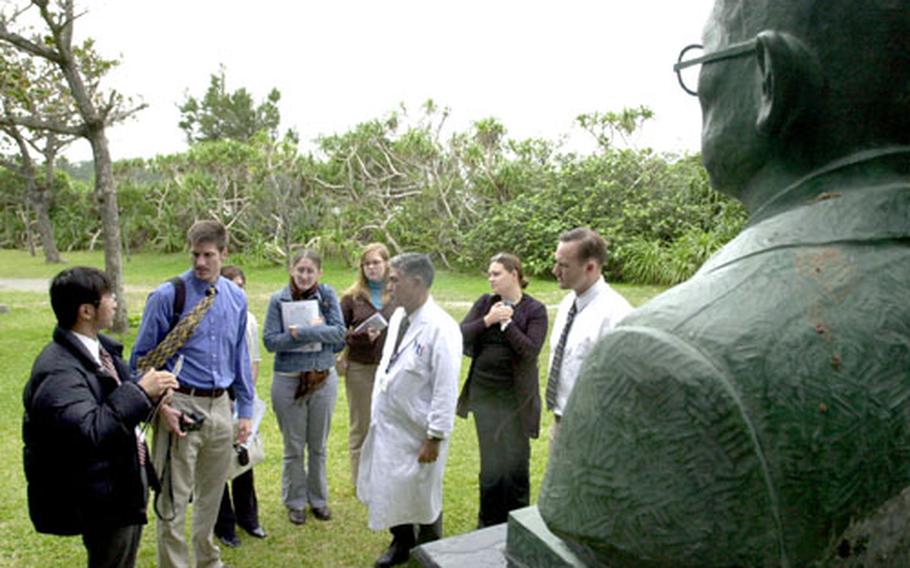 U.S. Naval Hospital Okinawa staff members and Japanese interns from the hospital toured Airaku En, a former Japanese national leprosy sanitarium, Tuesday with Dr. Kazuo Yamauchi, center in the white coat, the director of the community. In the foreground is a statue of the community’s founder, Keisei Aoki.