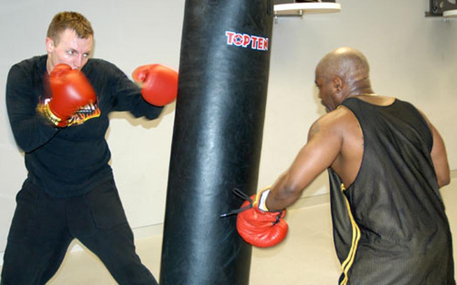 Sgt. Jan Ohrstrom, 1st Battalion, 33rd Field Artillery Regiment, left, works on the bag with another student during the one of the free boxing clinics held each Tuesday and Thursday at Warner Barracks in Bamberg, Germany.