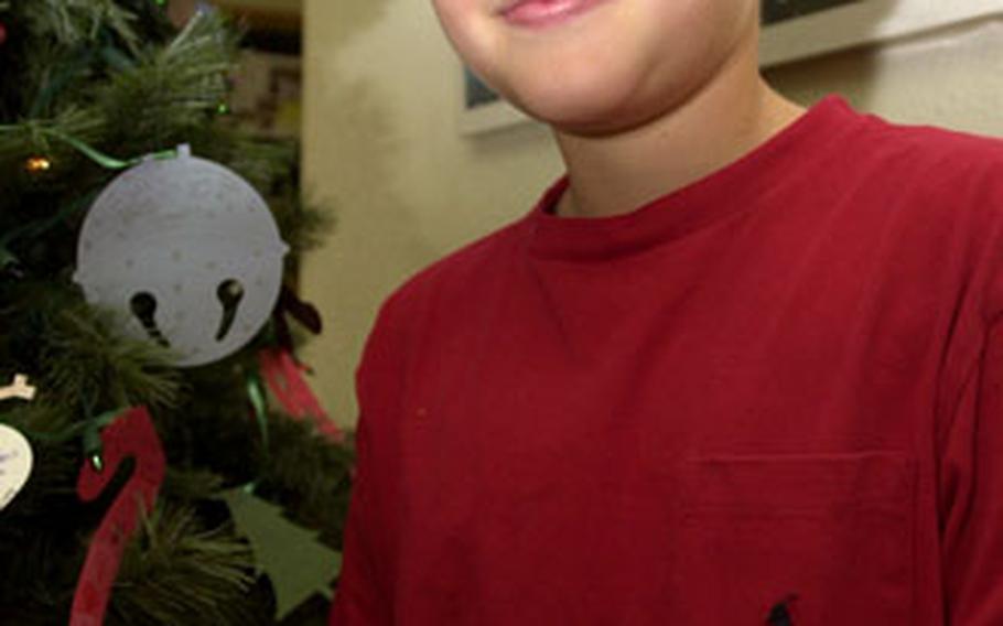 Kinser Elementary School fifth-grade student Jeffrey Black stands by an ornament he made, which wishes his family a good Christmas and that his sister gets everything she asked for.