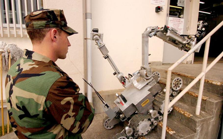 Chief Petty Officer Isaac Callicrate monitors a bomb-removal robot as it climbs stairs during a drill at the Yokosuka Naval Base, Japan, post office.