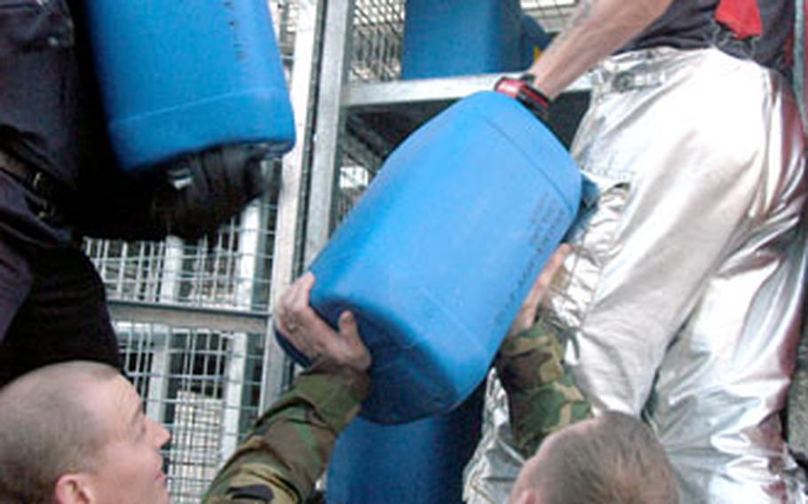 Ministry of Defence firefighters Gary Green, left, Alan Stewart, RAF Lakenheath’s Staff Sgt. Christopher Milby and firefighter Gary Wilson load five-gallon drums of aqueous film-forming foam onto a Sufflok Fire and Rescue Services truck.
