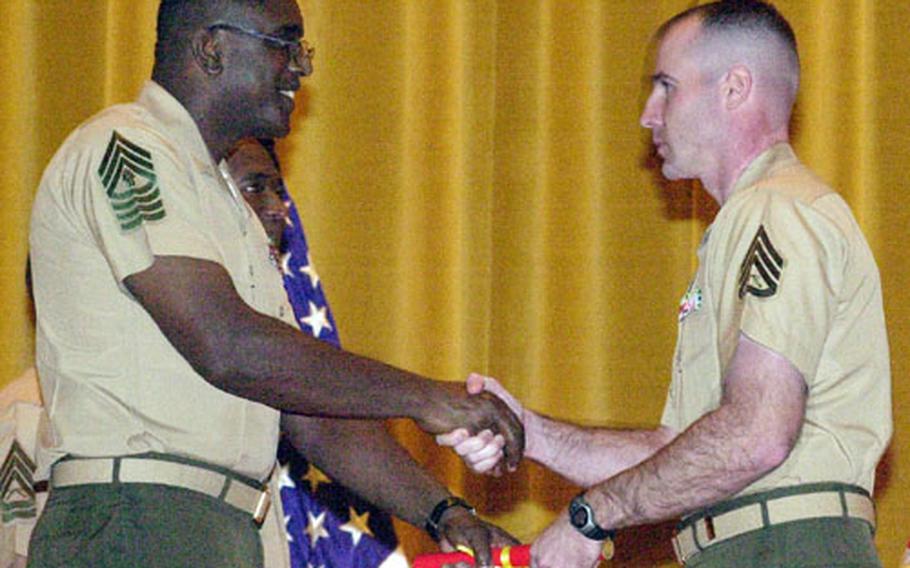 Staff Sgt. Christopher Kenly, right, receives a graduation certificate from Master Gunnery Sgt. Ira Thompson on Tuesday during the staff noncommissioned officer career course graduation ceremony at the Camp Hansen theater.