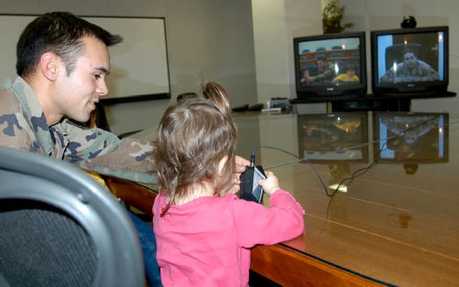 Staff Sgt. Christopher Ellis helps his daughter, Faith, 2, speak into a microphone to her mom, Senior Airman April Ellis, who’s deployed to Balad Air Base, Iraq. They were able to see each other for the first time since September via a special holiday morale video teleconference arranged between Misawa Air Base, Japan, and Balad.