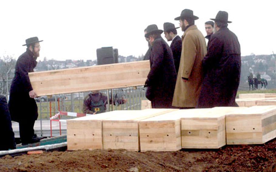Rabbis carry coffins containing the remains of Holocaust victims that were discovered in September at Stuttgart Army Airfield. The 34 set of remains were reburied Thursday just inside the main security gate. About 500 people attended the funeral.