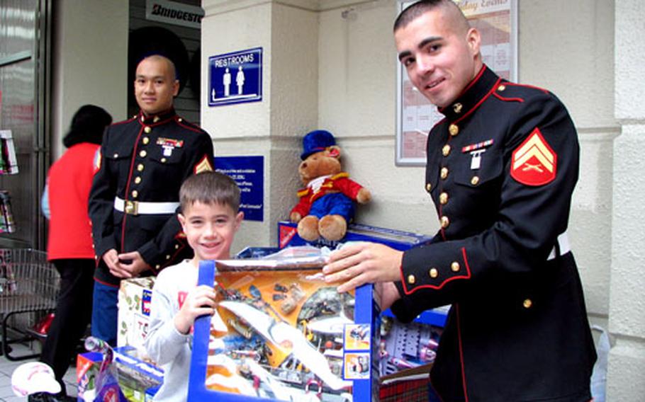 Luke Pacheco, 7, donates a toy to Cpl. Jason Areiza, 24, during the Toys for Tots Drive on Camp Foster Saturday. Volunteer Marines filled a bus with toys collected for needy children throughout Okinawa.