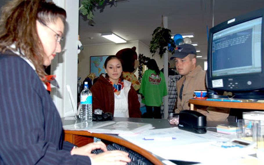 Ticketing agent Karen McLean helps customers Staff Sgt. Ryan Sleight and his wife, Jill, book a Tokyo trip Saturday during the grand opening of Misawa Information Tickets and Travel (ITT).
