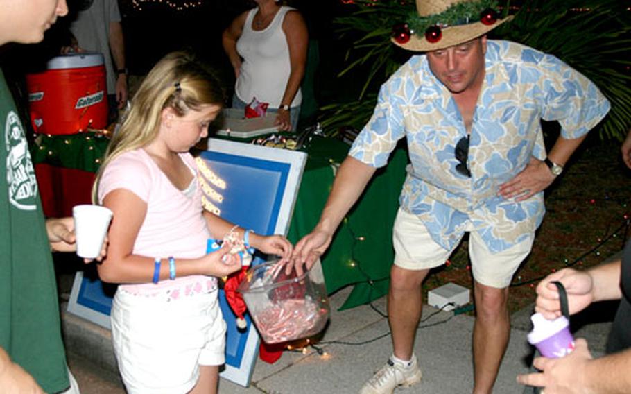 Lizzie Koorey, 9, picks out candy offered by Senior Master Sgt. Pete Tetreault. The walk in the base’s housing area is an annual tradition aimed at stirring up some Christmas spirit — even if it is 85 degrees and sunny.
