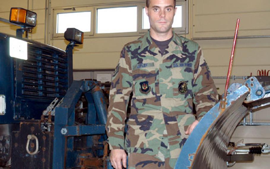 Staff Sgt. Chad Lepley stands in front of one of RAF Mildenhall's 10-ton snowplows.