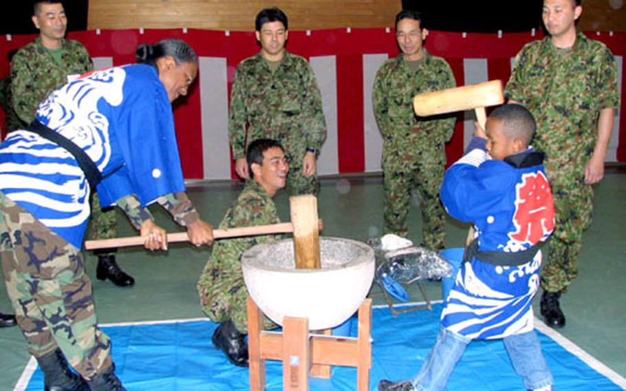Army Lt. Col. Maria Drew, 58th Signal Battalion commander, pounds rice with her son, Zulymon, 6, during a ceremony Wednesday at the Japan Ground Self-Defense Force's Camp Naha.