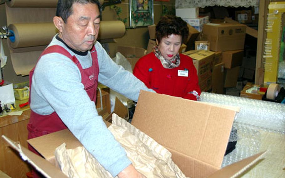 Masataka and Masako Komorida, a retired couple who have operated the Navy Exchange Pack ’N’ Wrap shop at Sasebo Naval Base for three years, say November and December are their busiest months as base personnel ship Christmas gifts to the United States and elsewhere.