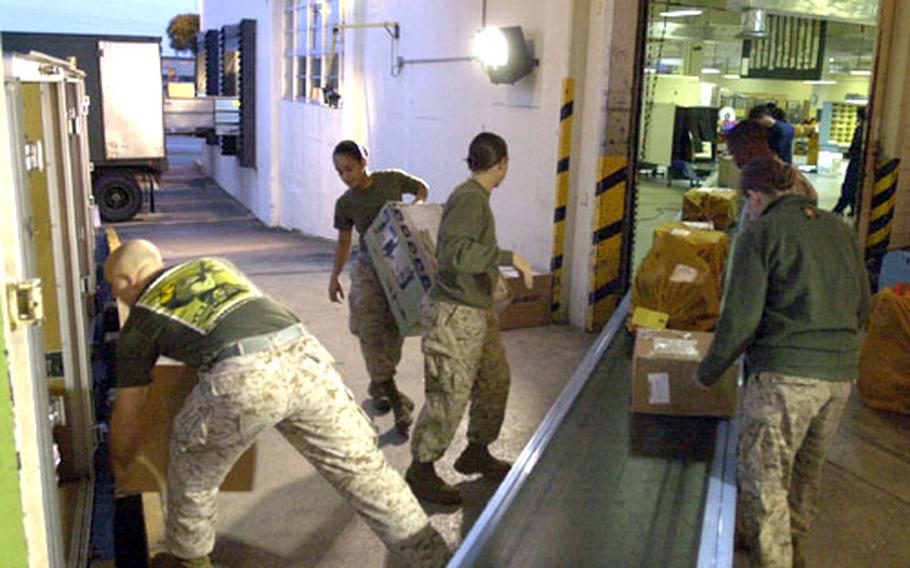 Marines pull packages off a conveyor belt and load them into waiting delivery trucks at the Consolidated Postal System building on Camp Kinser early Wednesday.