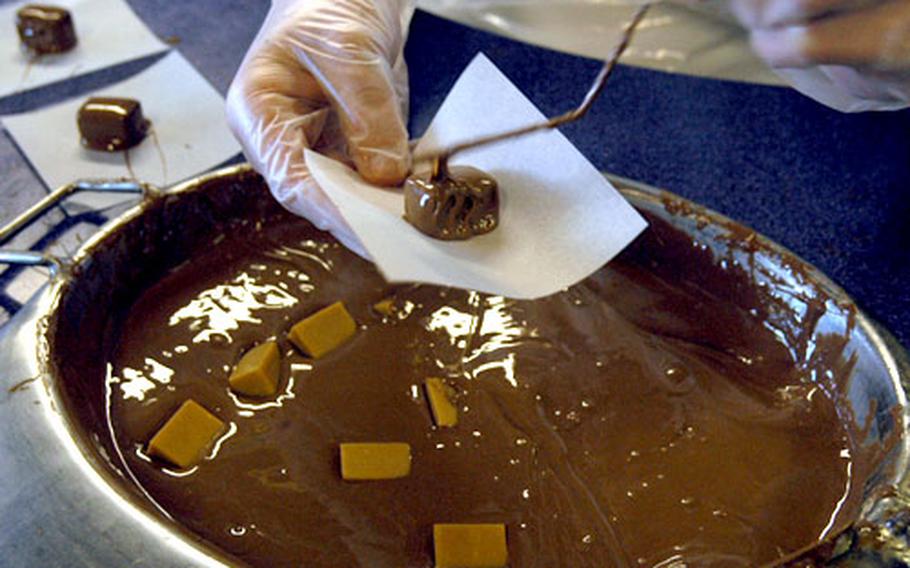 A worker in the demonstration area of Cadbury World hands out samples of fudge dipped in warm, liquid chocolate.