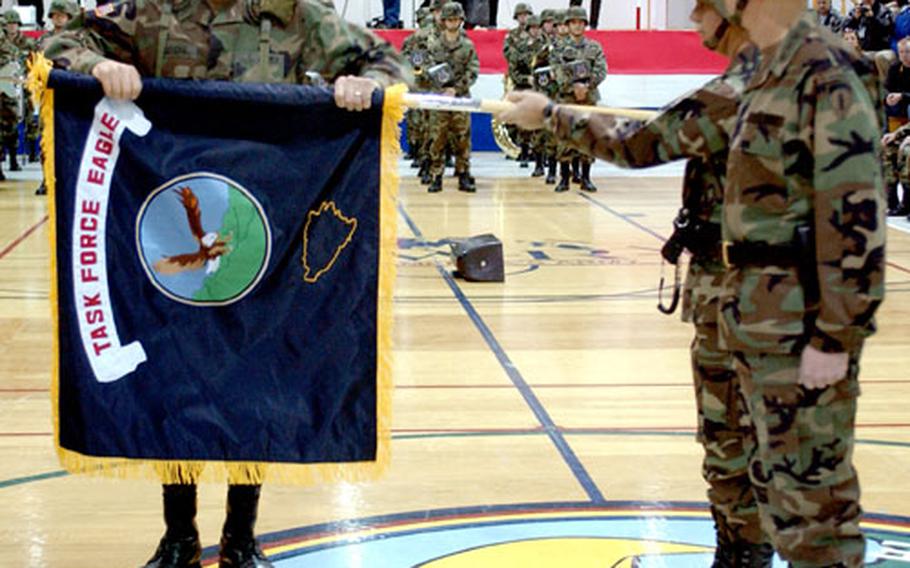 As Gen. B.B. Bell, commander of U.S. Army Europe, right, watches in November 2004, Task Force Eagle’s Command Sgt. Maj. Thomas Severe rolls the task force’s colors as they are held by Brig. Gen. Timothy Wright, the final task force commander.
