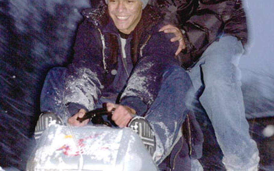 Army Sgt. Shane Ferguson (back) pushes his brother, David, down a snow-covered hill at Kapaun Air Station on Wednesday.