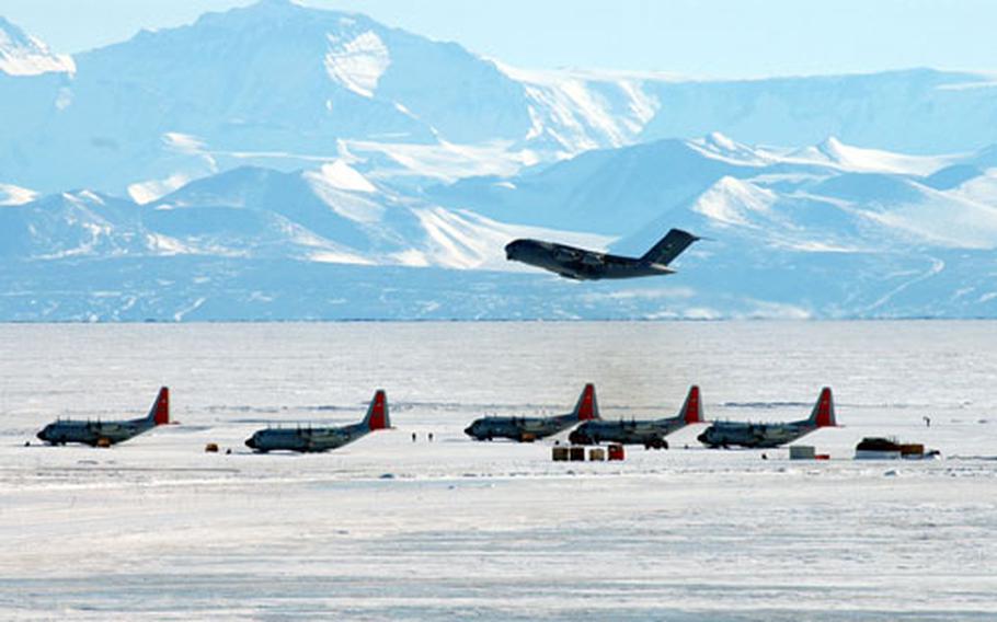 A C-17 from McChord Air Force Base, Wash., takes off from the ice runway at McMurdo Station, Antarctica. On the runway, LC-130s, specially equipped with skis, wait to be loaded.