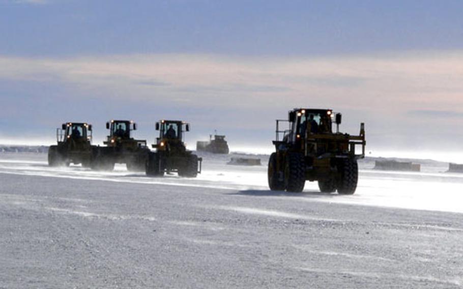 Forklifts approach a McChord C-17 at the Sea Ice runway near McMurdo Station to download cargo.