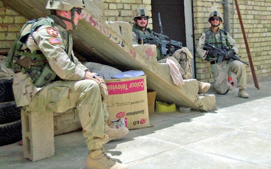Soldiers from 1st Battalion, 9th Infantry seek some shade during a mission in July as they listen to the preachings of local Imams. From left to right are 1st Lt. Judson Bennett, Capt. Kevin Capozzoli and 1st Lt. Matt Miller.