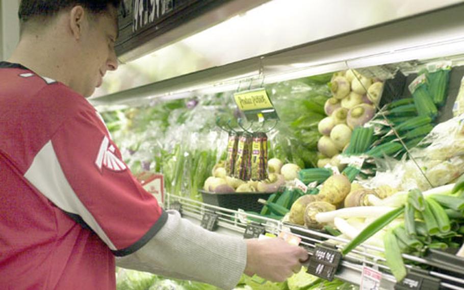 Marcus Hunt, customer service manager, places tags Friday to let customers know what is healthy to buy at the commissary at Yokosuka Naval Base, Japan.
