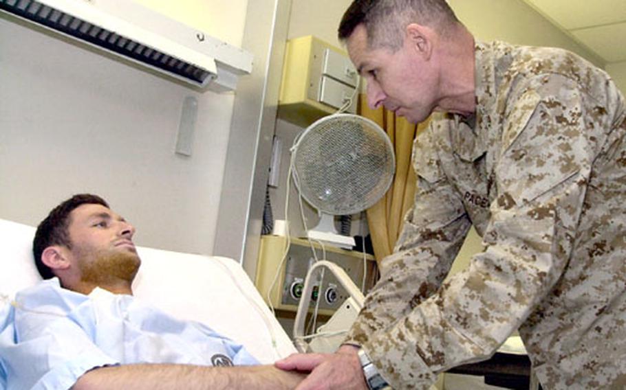 Gen. Peter Pace, chairman of the Joint Chiefs of Staff, shakes hands and gives a coin to Army National Guard Sgt. Joshua Henniger on Tuesday at Landstuhl Regional Medical Center in Germany. Henniger was injured by mortar fire in Iraq just three days before he was scheduled to return to the U.S.