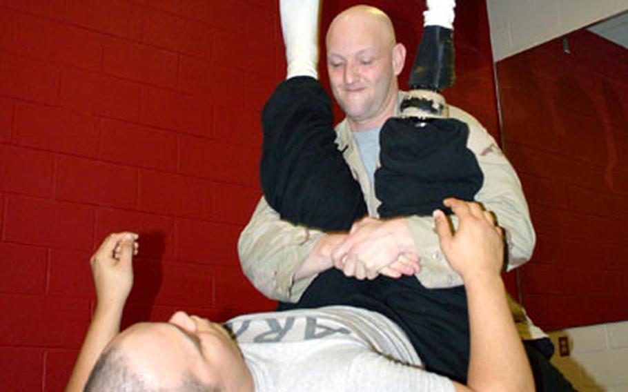 1st Lt. Frank Washburn wrestles with Sgt. Orlando Gill at Walter Reed Army Medical Center on Friday.